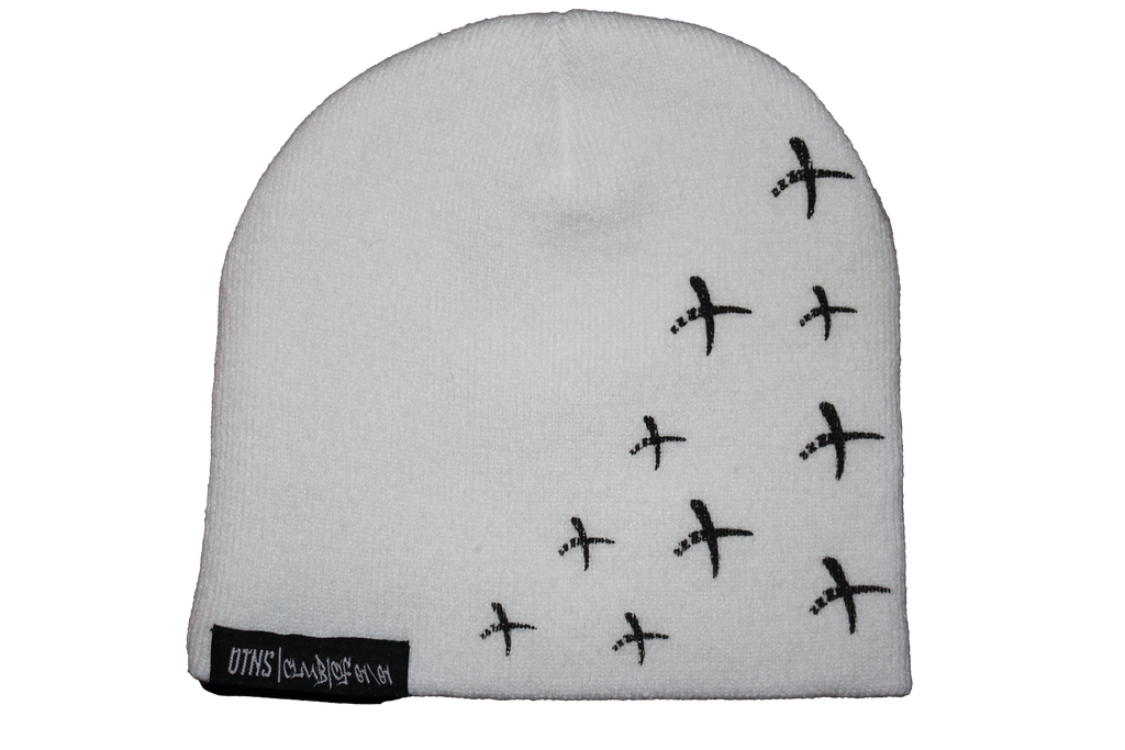 White OTNS beanie with black cross design and woven tags, stylish and warm perfect for Y2K fashion.